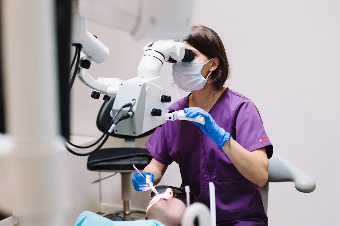 A dentist using a microscope and modern technology during a patient examination in a dental clinic.