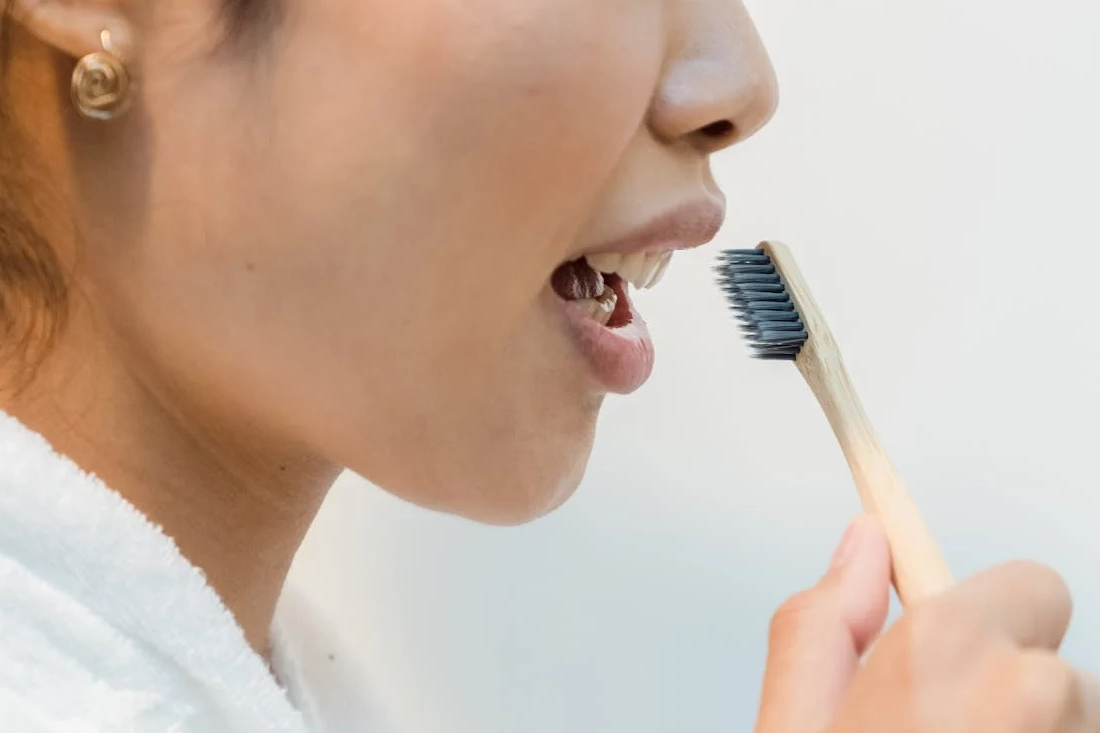 Close-up of a woman practicing oral hygiene with an eco-friendly bamboo toothbrush.
