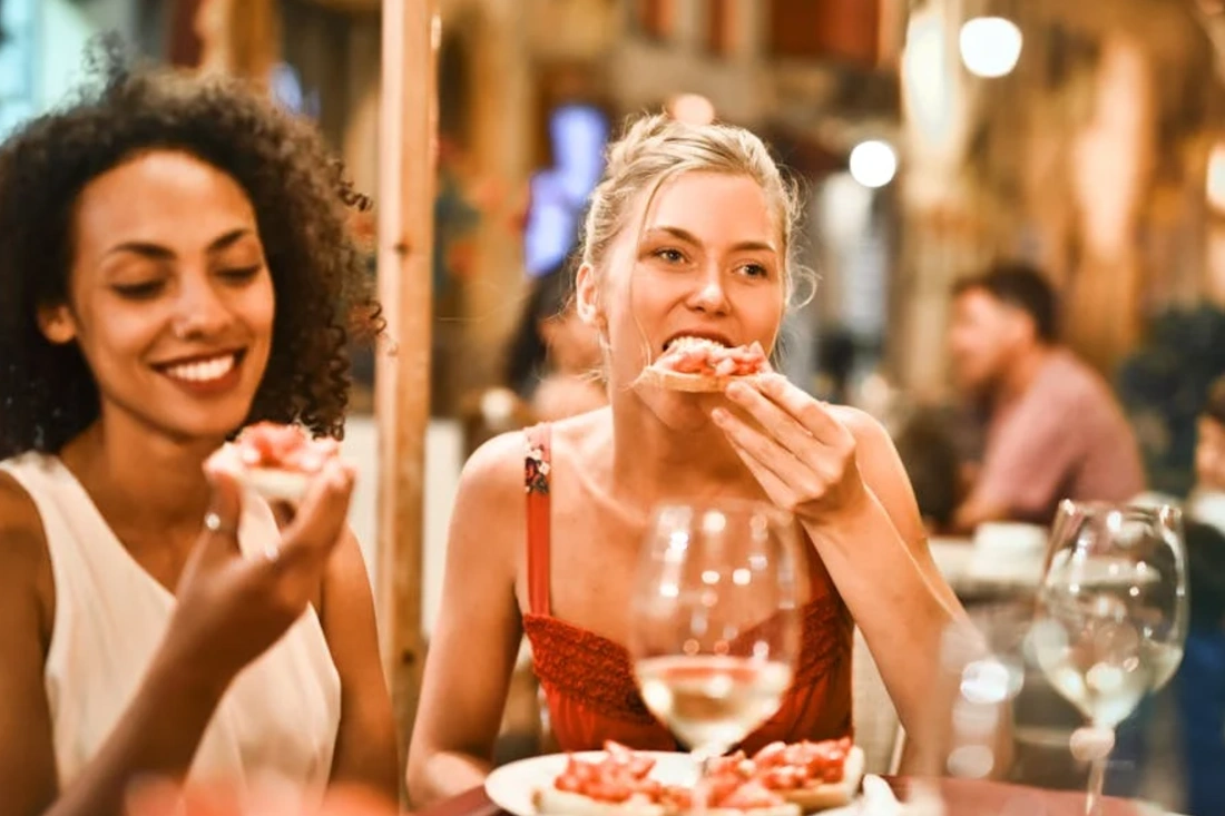 women enjoying bruschetta and wine at a vibrant outdoor restaurant.