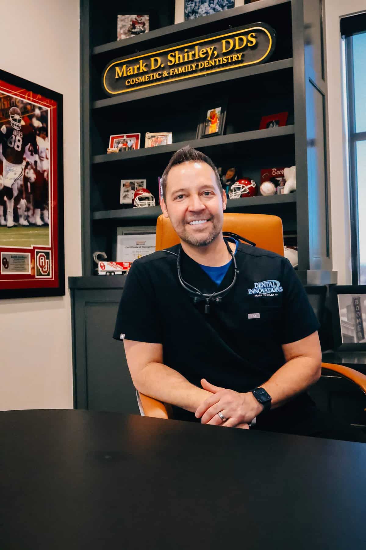 Dr. Mark Shirley DDS happily sitting at his desk