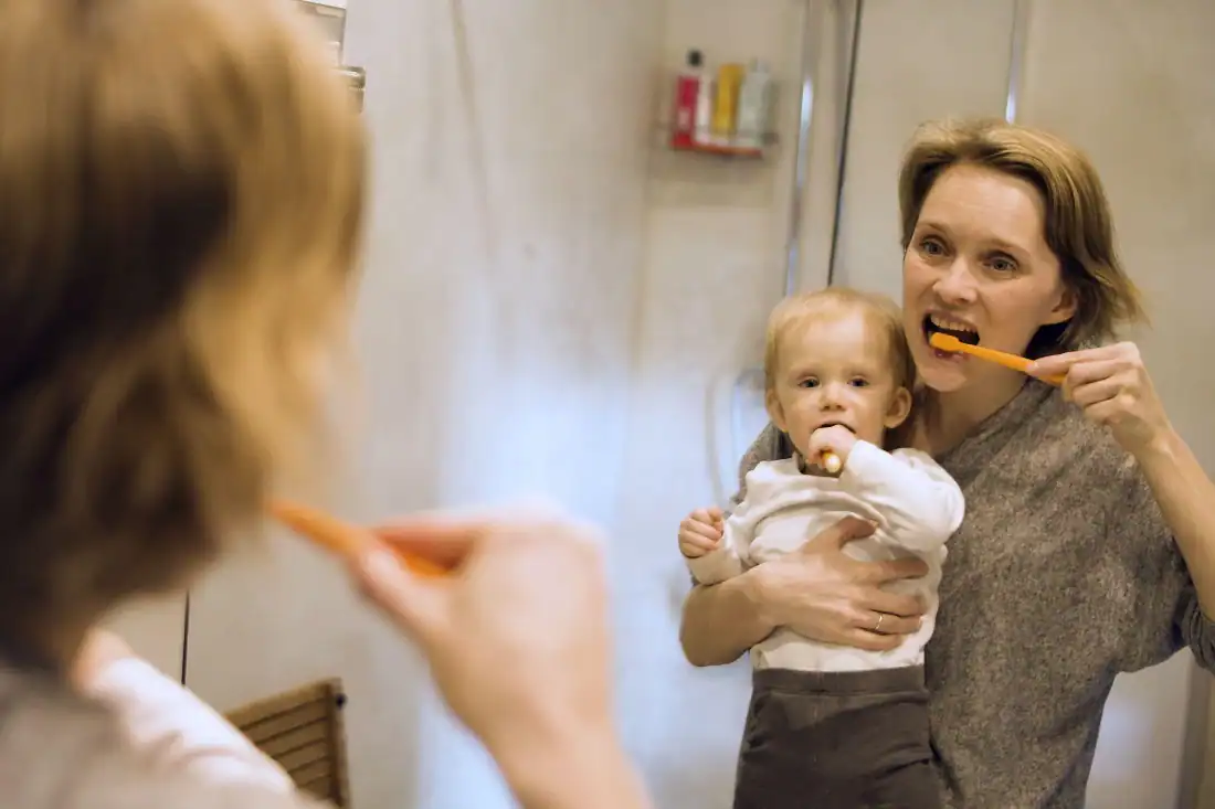 Parent and child brushing teeth together for good oral hygiene