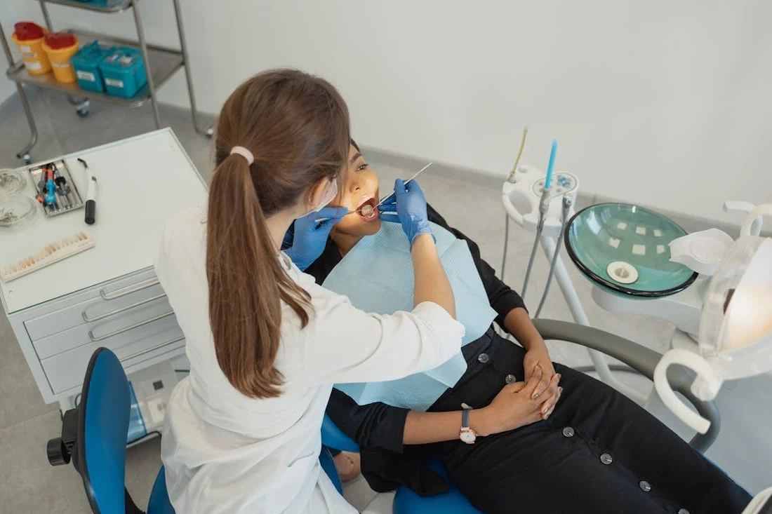 A healthcare professional conducting a dental check-up with patient in clinic.