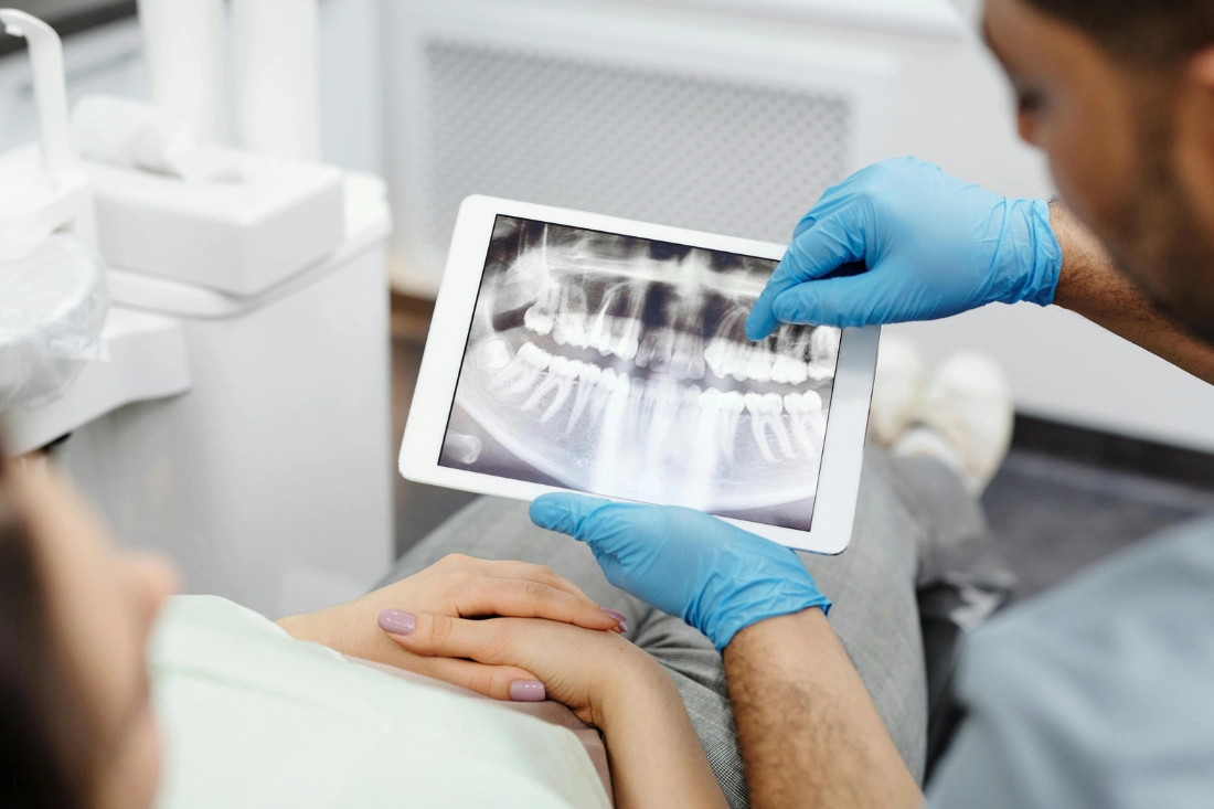 Person wearing blue latex gloves holding white tablet computer.