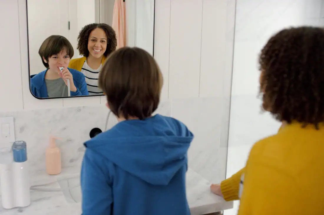 mom helping boy brush his teeth