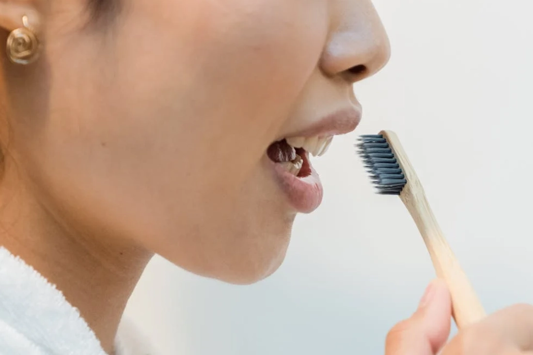 Close-up of a woman practicing oral hygiene with an eco-friendly bamboo toothbrush.