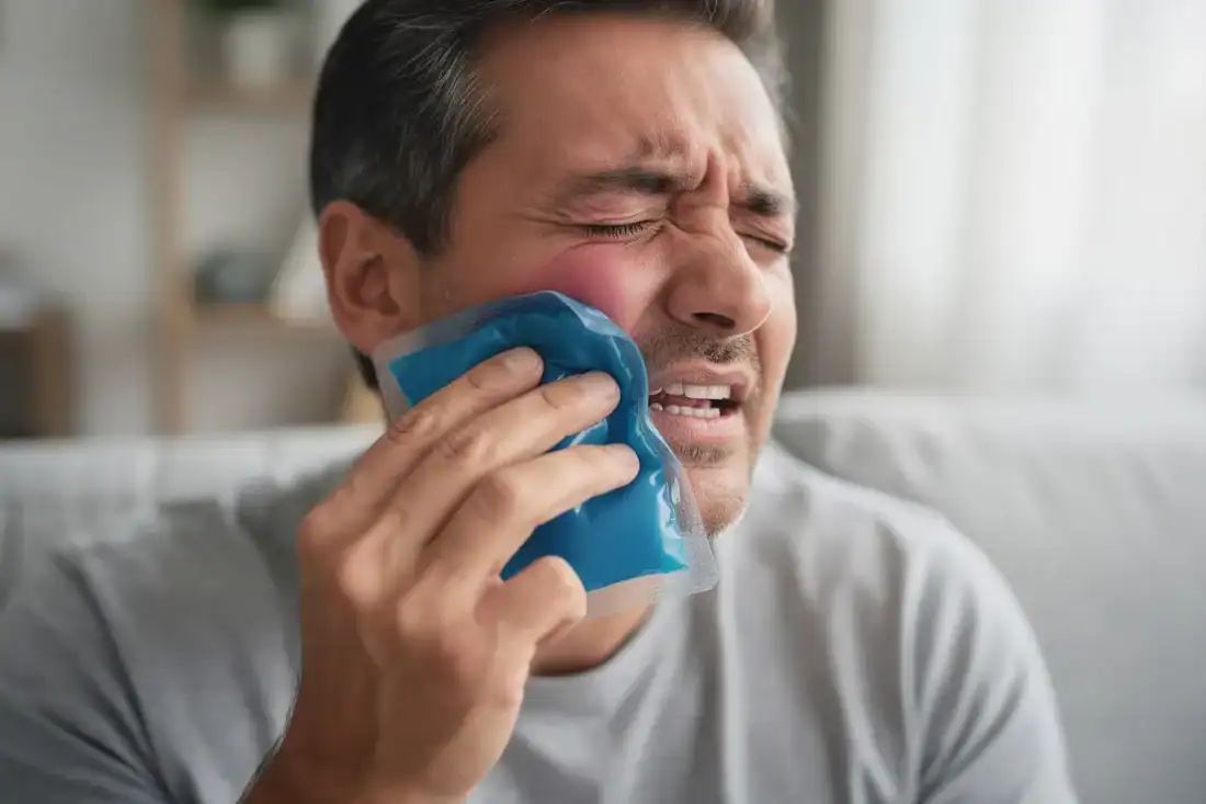 a man applying a cold compress due to tooth pain