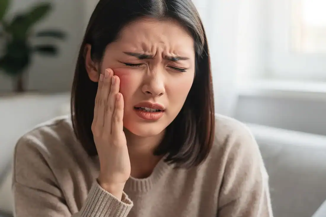 a woman holding her jaw in discomfort