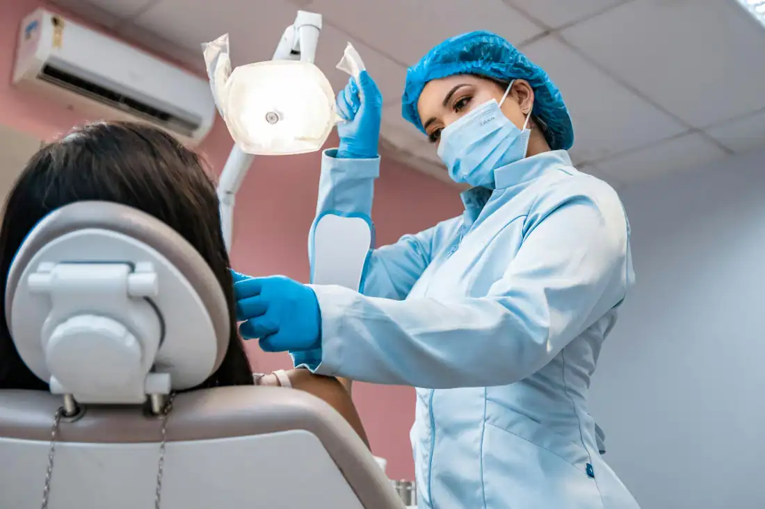 dentist adjusting light next to patient in chair