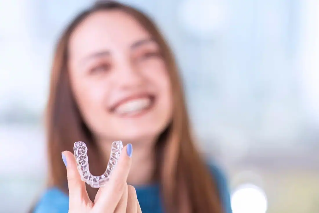 woman smiling holding invisible aligners