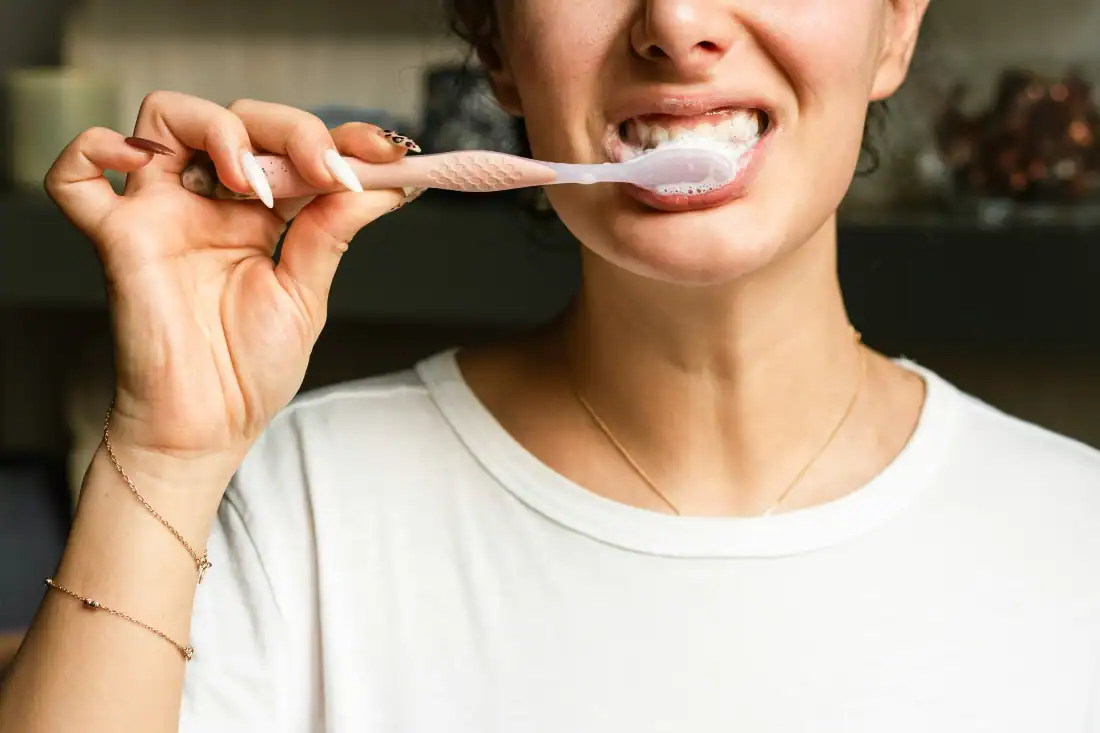 young woman brushing teeth in bathroom, closeup, opy space